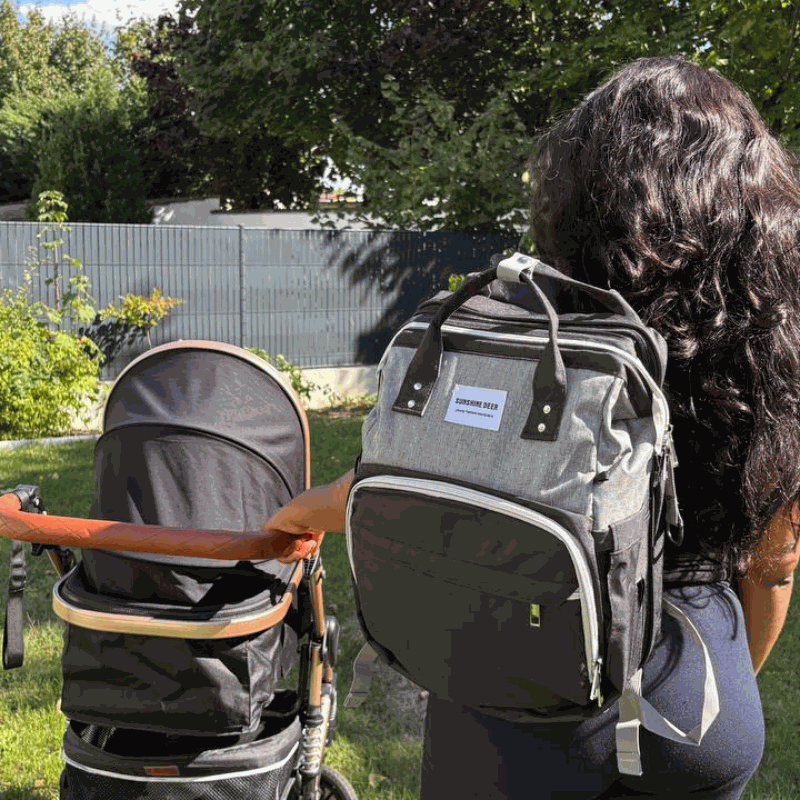 Sac à dos pratique gris en tissu avec poches zippées, porté avec un lit bébé pliable intégré