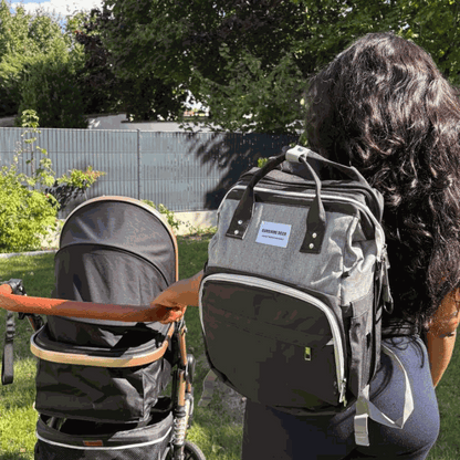 Sac à dos pratique gris en tissu avec poches zippées, porté avec un lit bébé pliable intégré