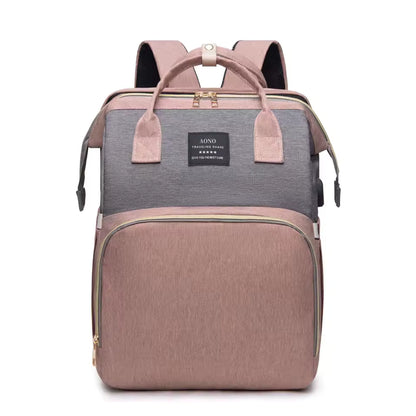 Sac à dos pratique rose poudré et gris en tissu, avec poignées, bretelles et plusieurs poches zippées.